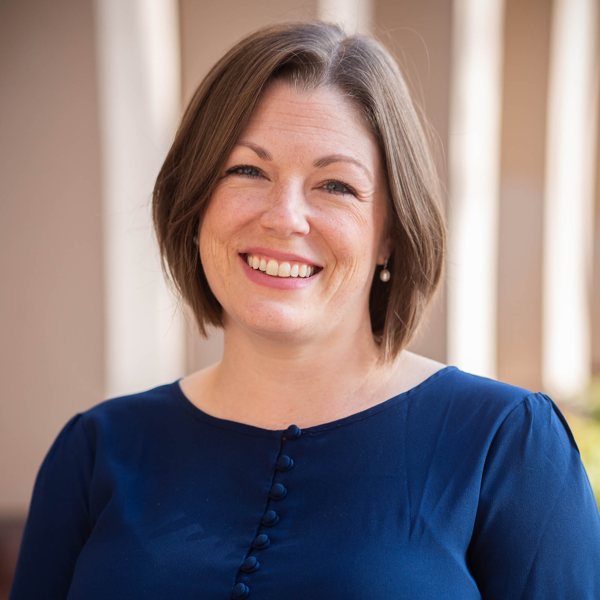 White woman with bob in blue shirt, smiling