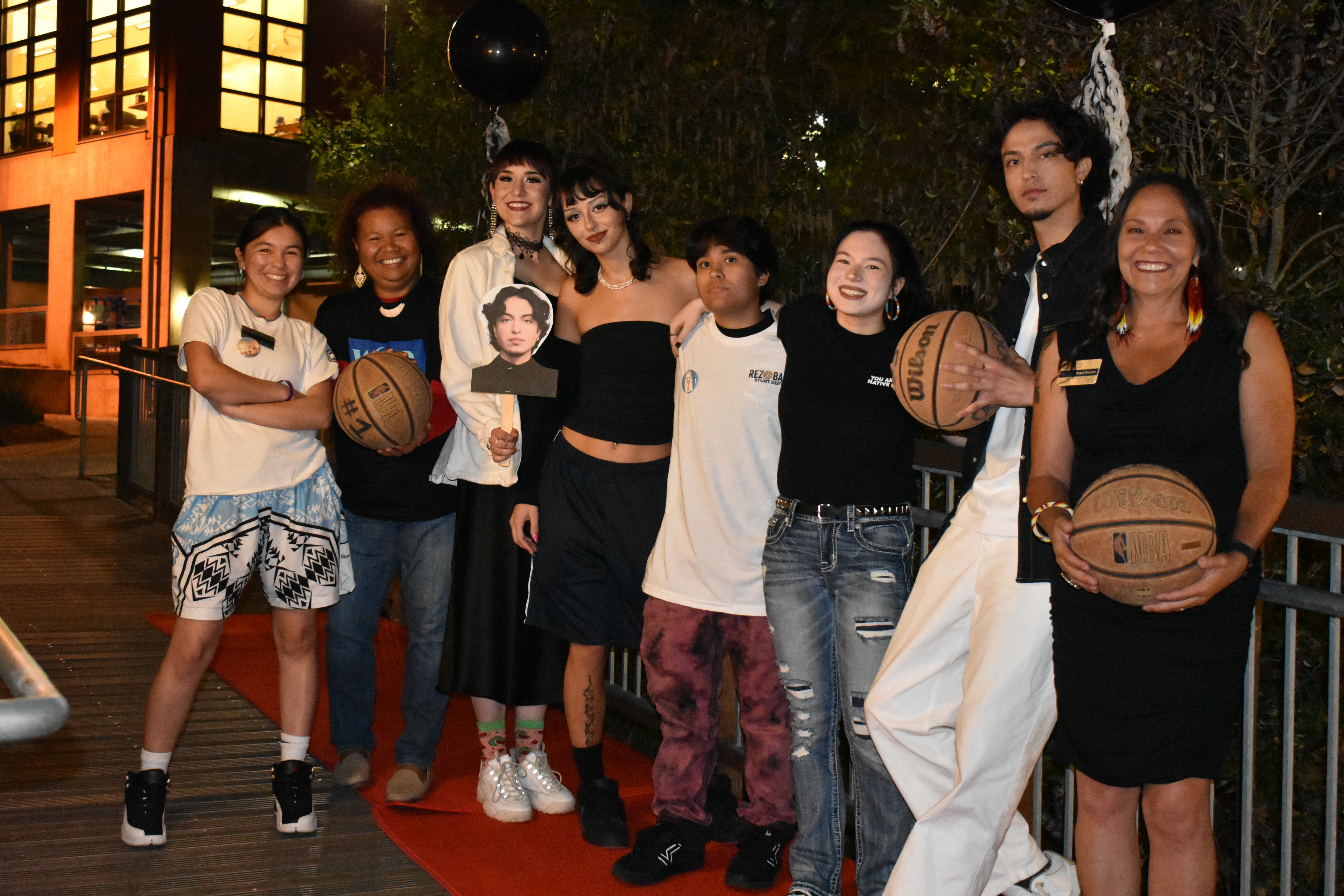 A group of smiling young people holding basketballs