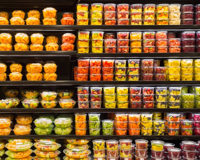 A grocery store case filled with plastic containers of cut fruit