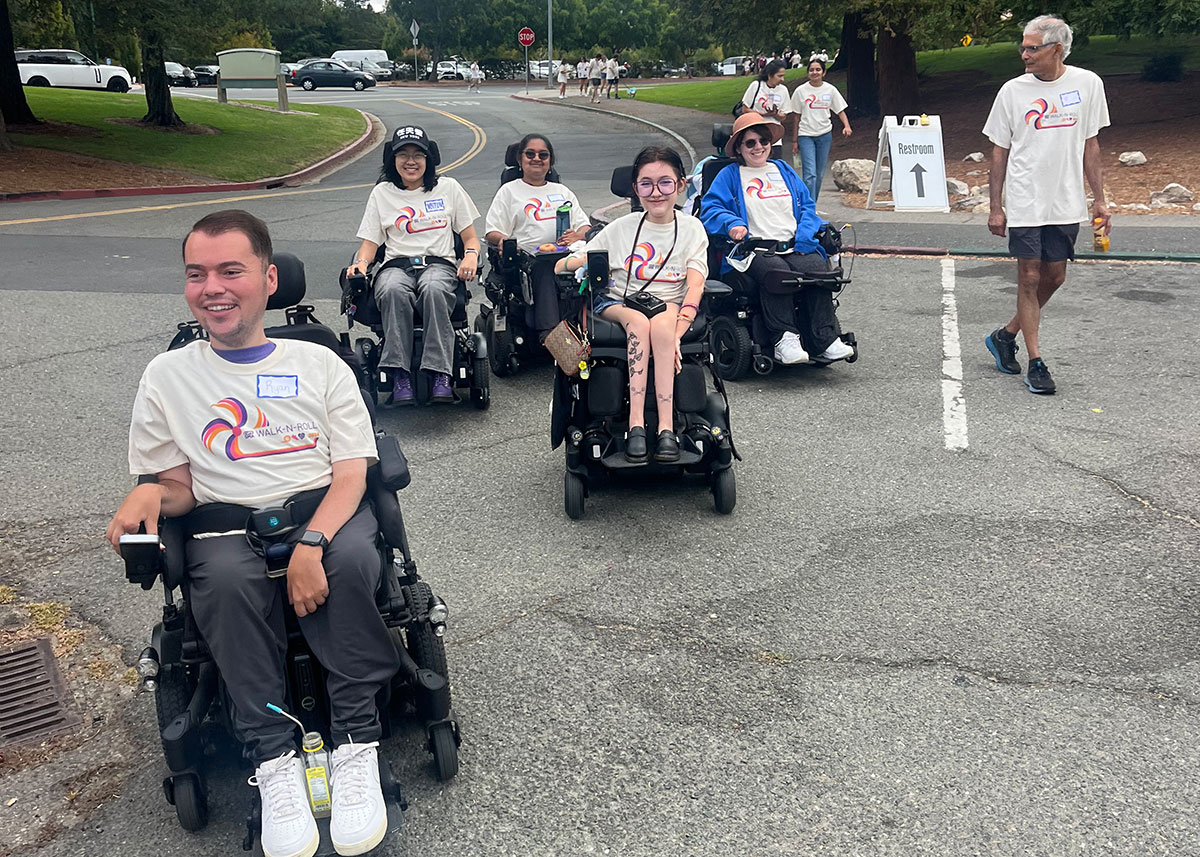 Ryan Manriquez and 7 other people at an advocacy event for Cure SMA, wearing matching t-shirts. Ryan and four fellow participants use motorized wheelchairs.