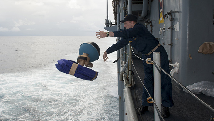 A man throws buoys off the deck of a ship