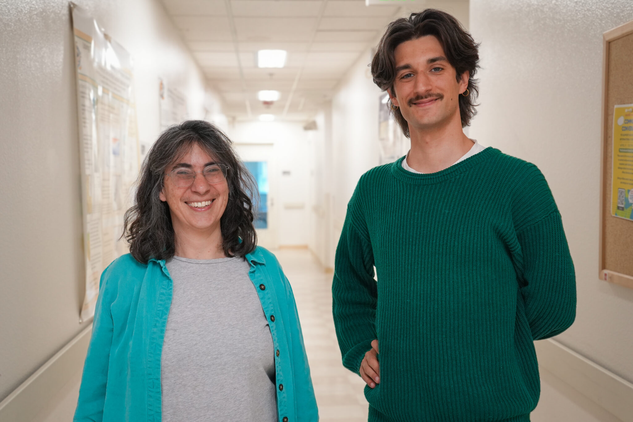 Two researchers, a woman with glasses and shoulder length hair on the left, and a taller young man with a mustache on the right
