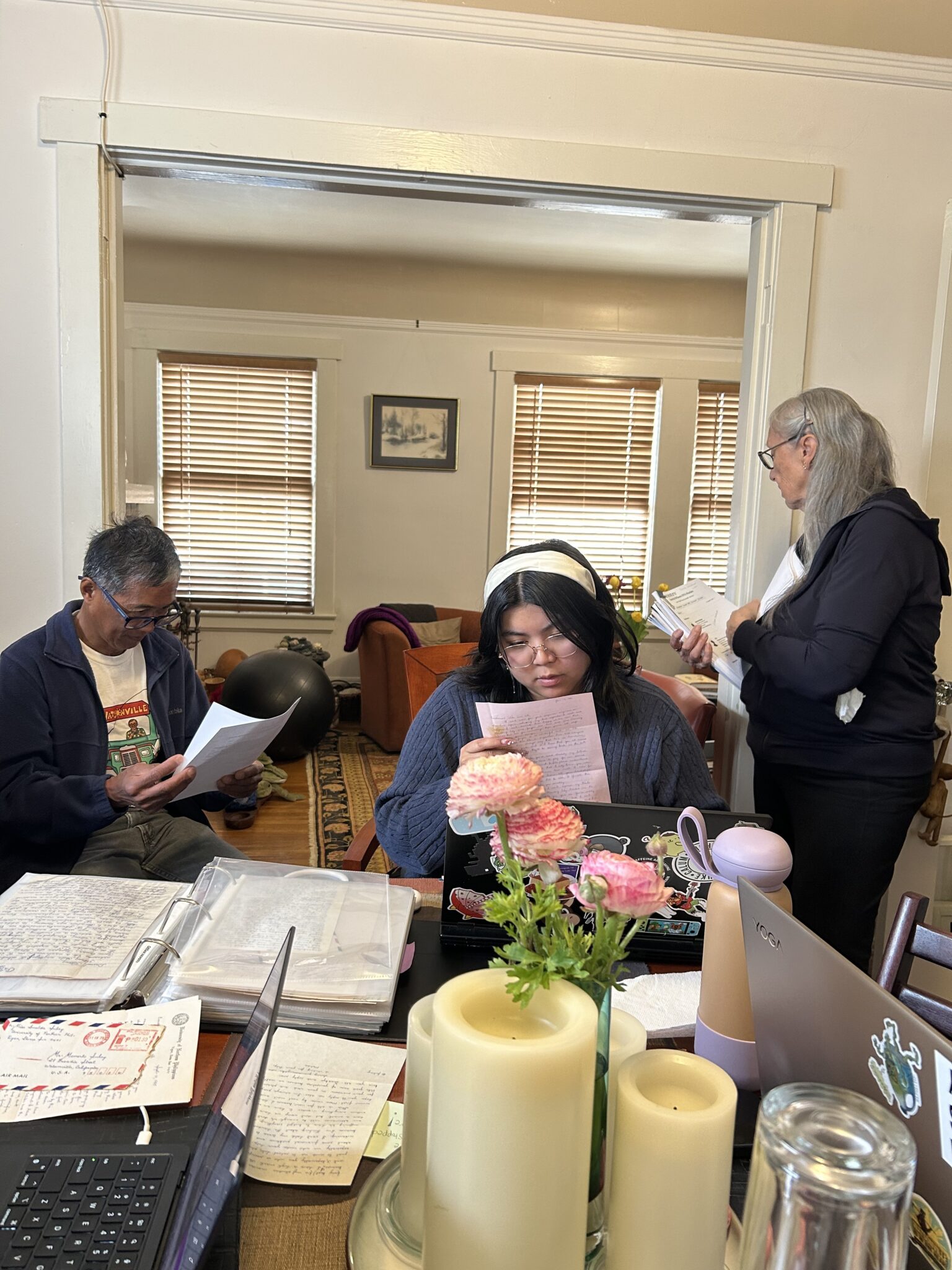 In the interior of a home, three people leaf through papers