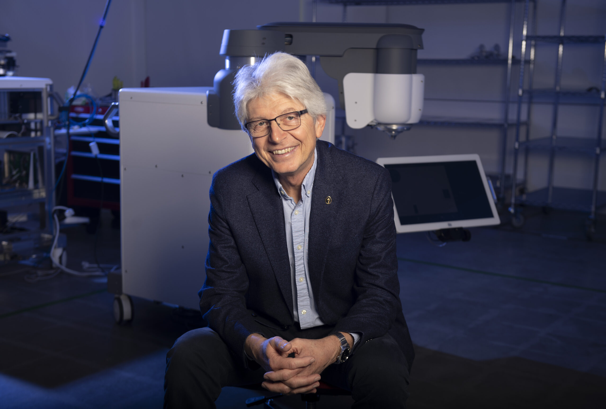 Tibor Juhasz sits in front of a large medical machine in a darkened operating room