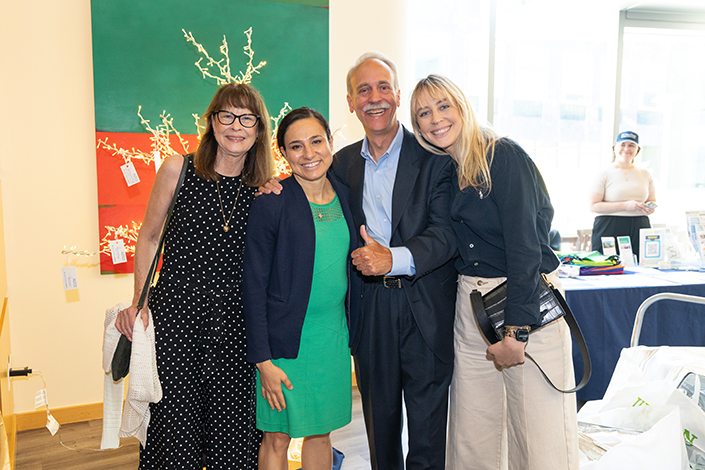 Four people pose for a photo, with a mustached man in the middle giving a thumbs up