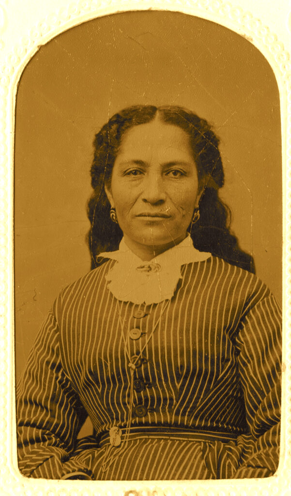 A worn, sepia portrait of a Hawaiian woman wearing a high-necked dress