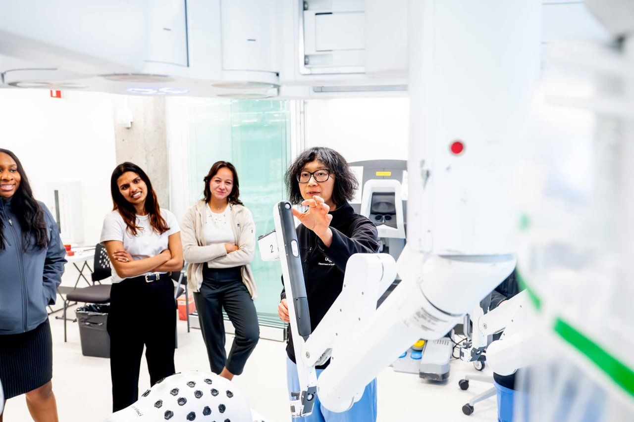 A teacher shows three students how to use a surgical robot.
