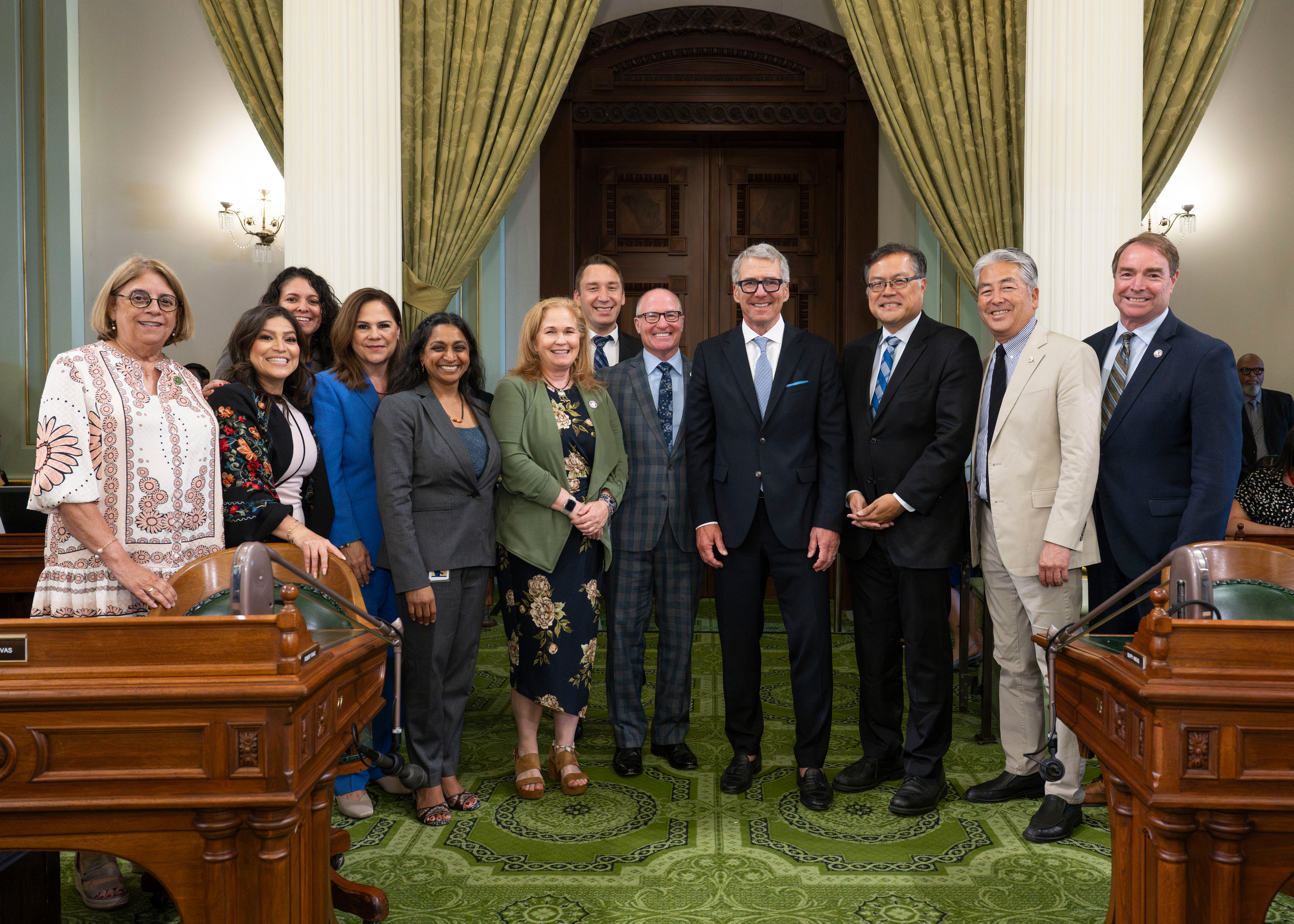 President Milliken in a room with a number of legislators, all standing together for a photo