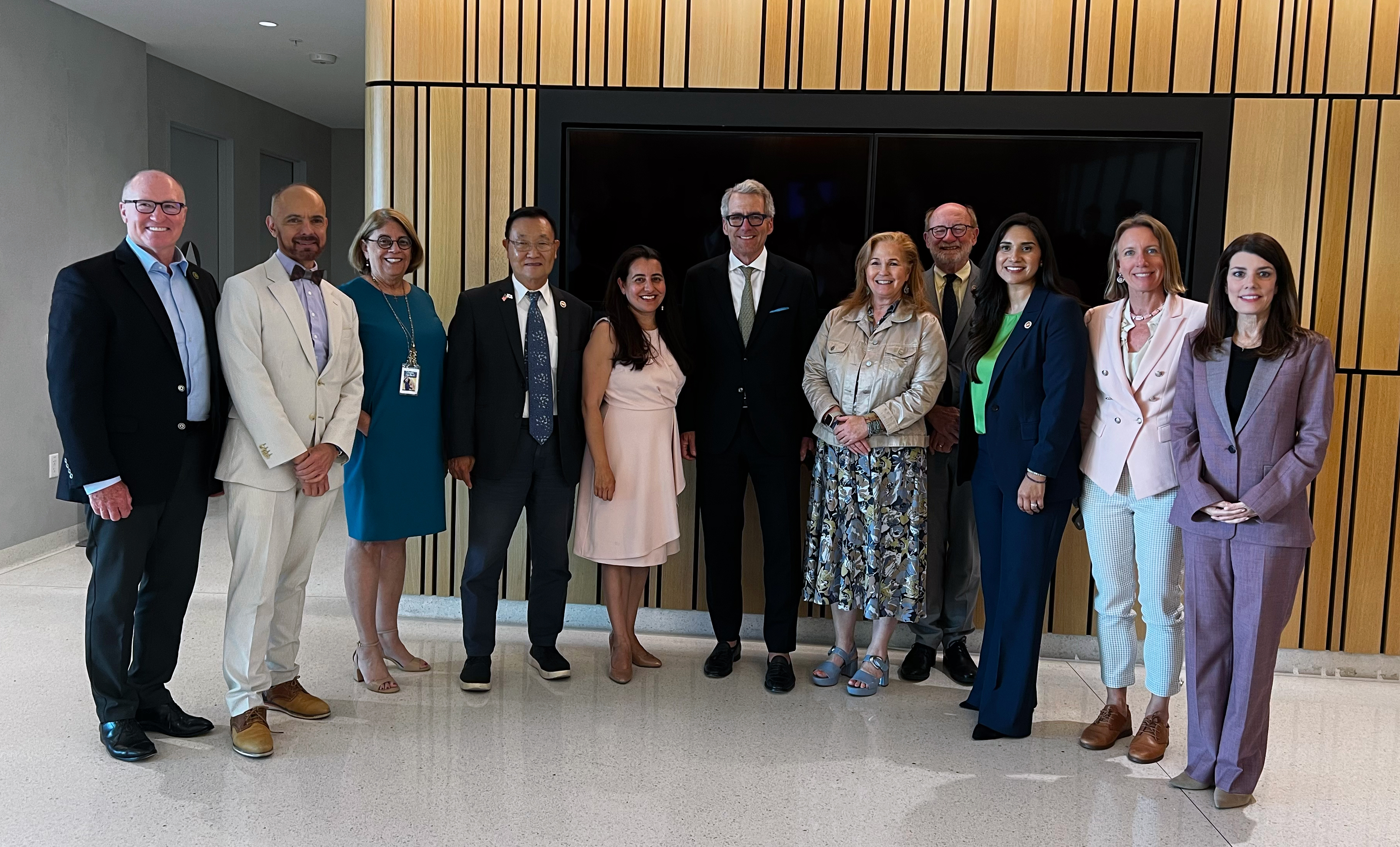 A group of legislators and UC President Milliken stand together in a group photo, smiling