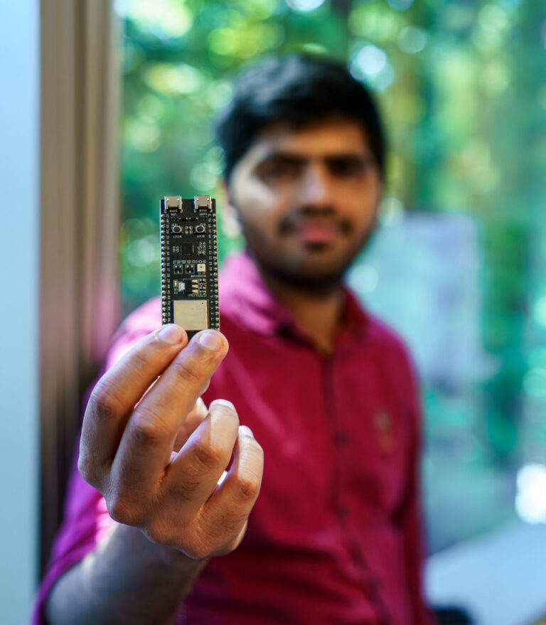Nayan holds up an ESP32 chip.
