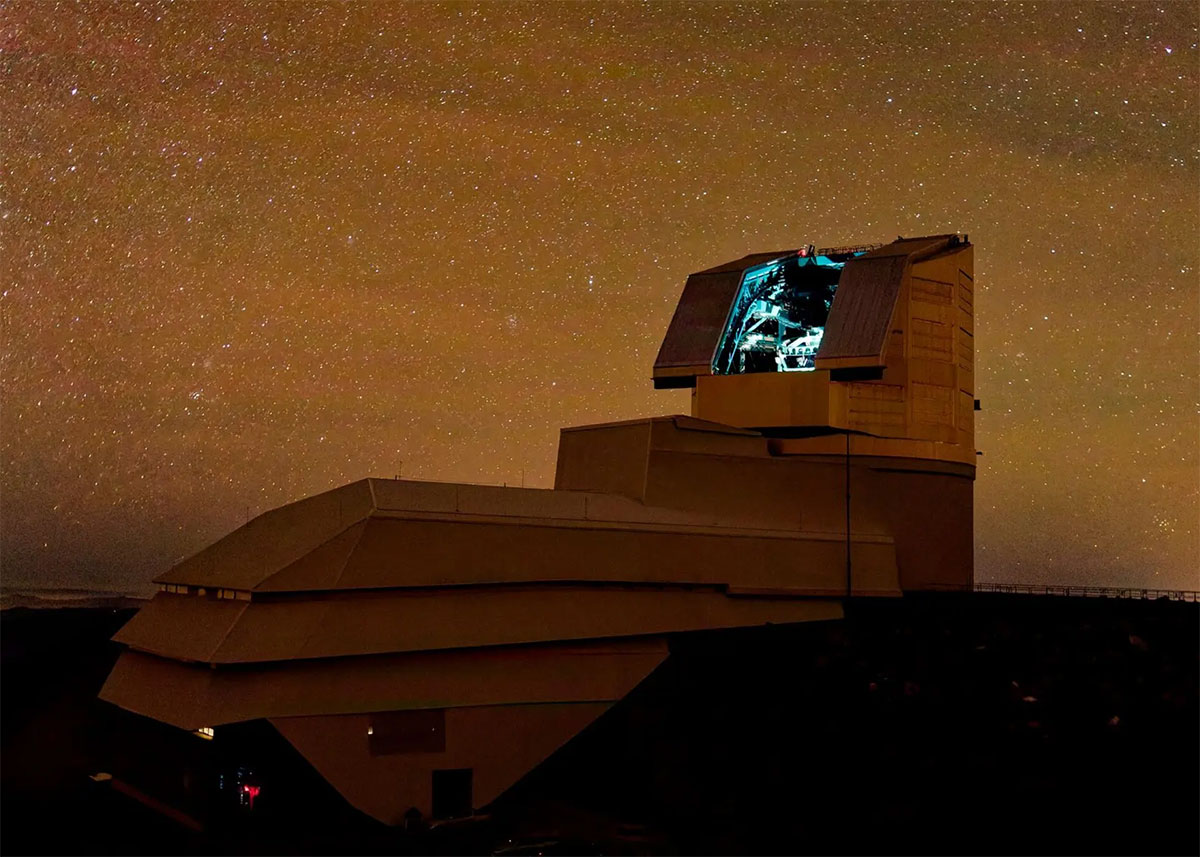A large telescope on a mountaintop at night under a starry sky