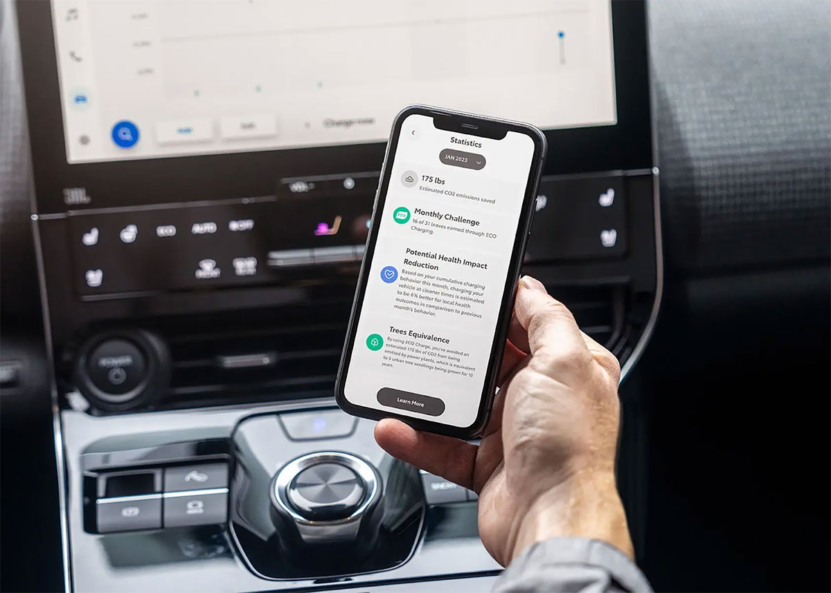 A man's hand holds a phone up near a car's center console