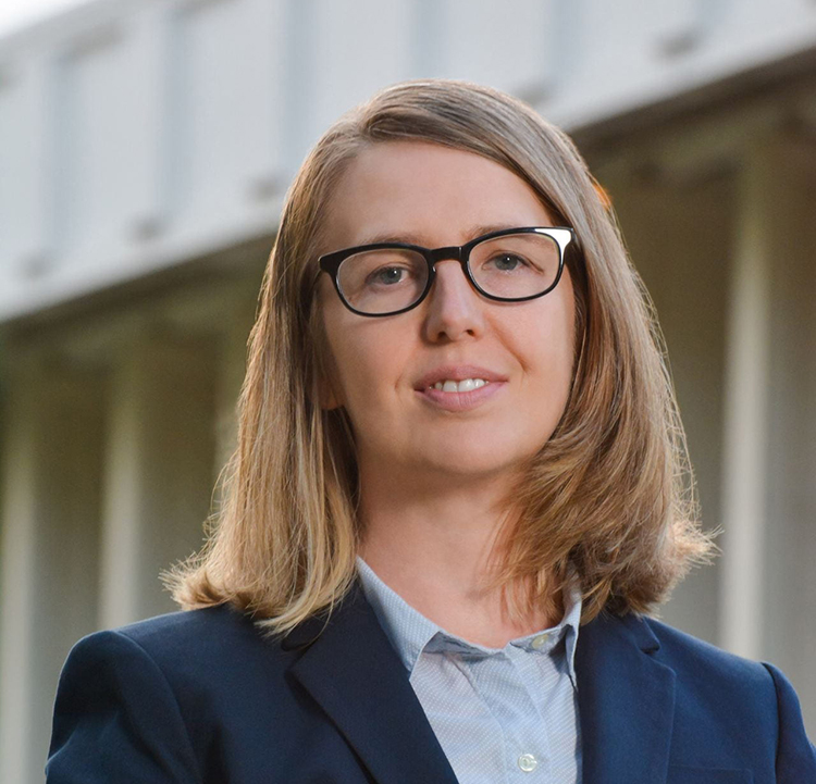 Woman with a bob and glasses wears a blue blazer in a headshot