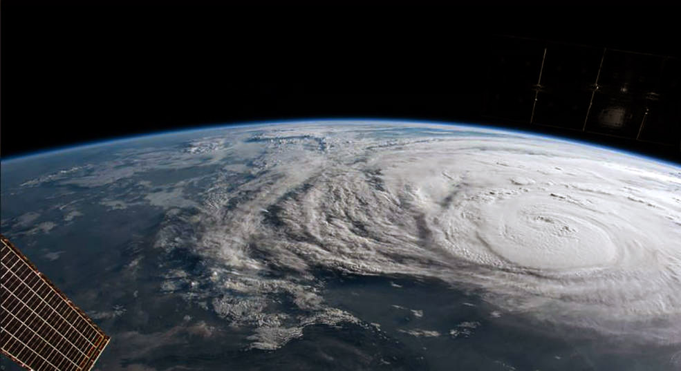 A massive hurricane seen from outer space with a satellite solar panel in the lower left corner