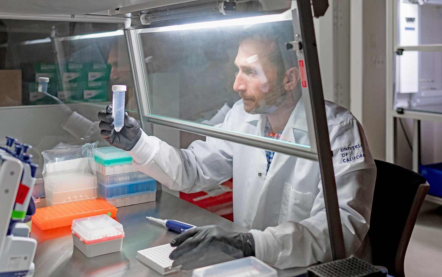 A man holds up a large vial in a lab