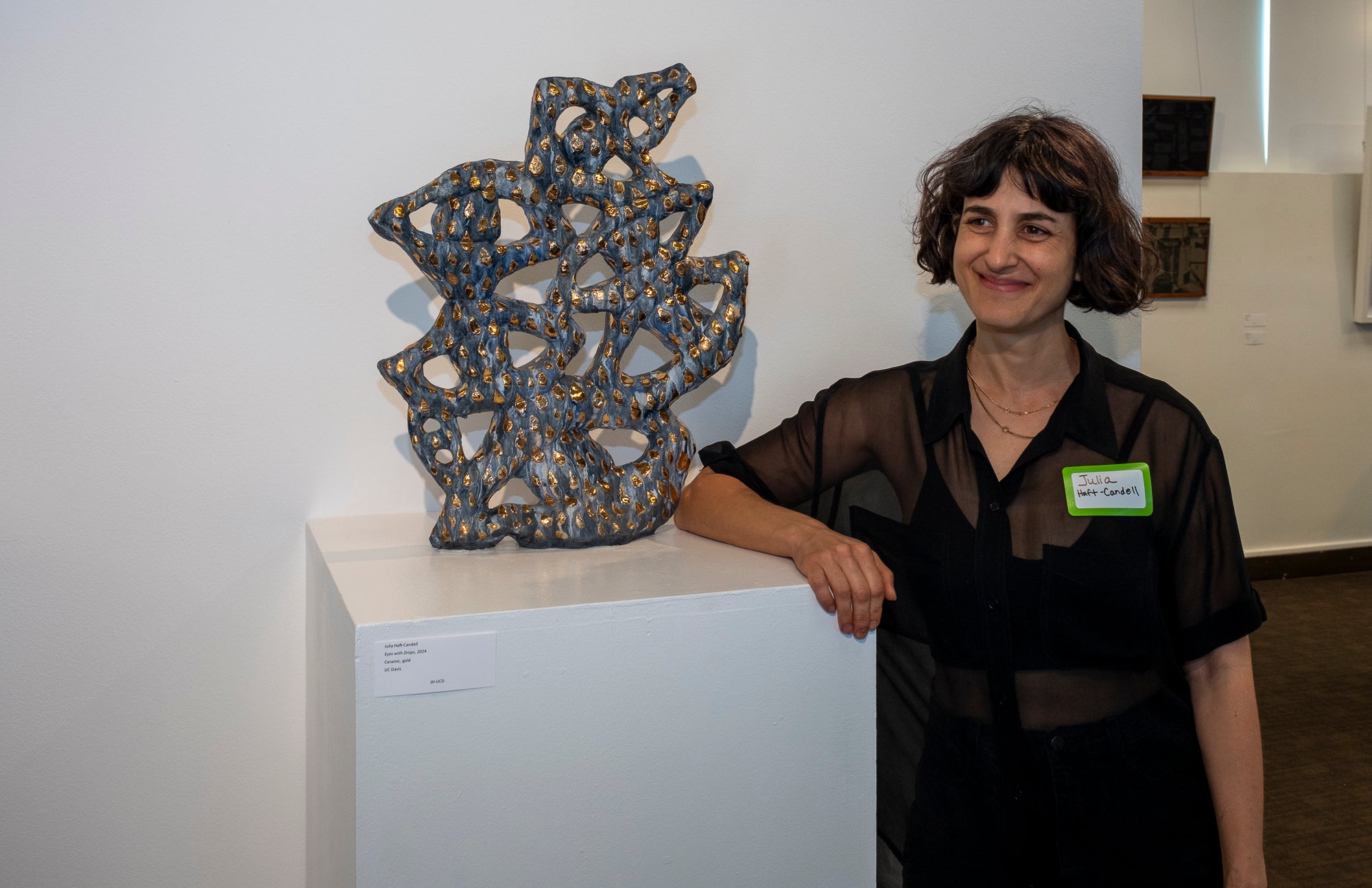 A student smiles next to a sculpture