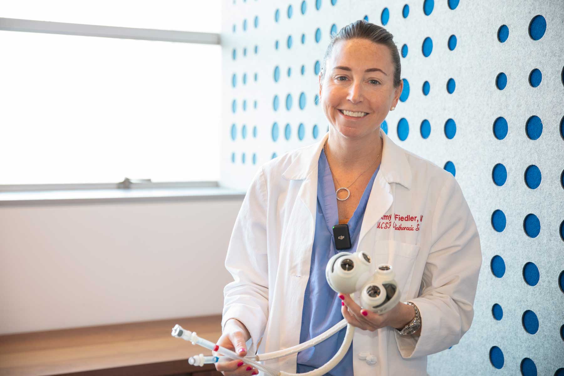A doctor smiles as she holds a device that operates as an artificial heart