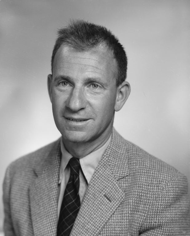 In a black and white photo, a man with a tie and jacket