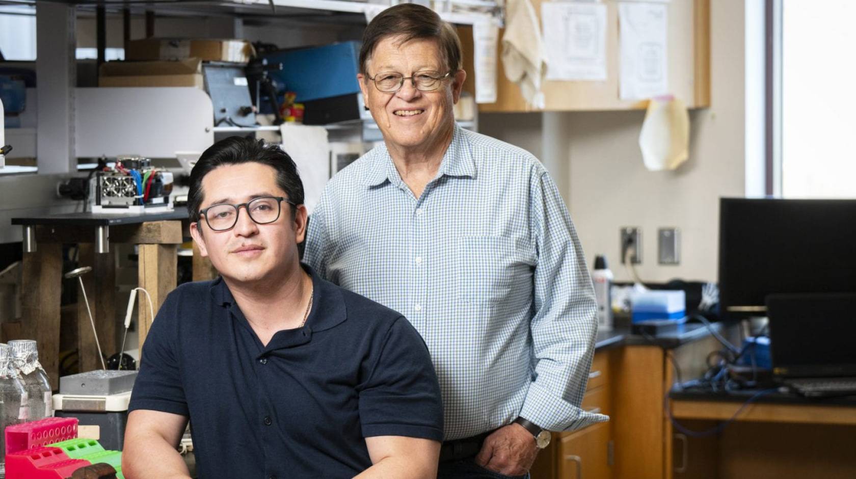 Two researchers wearing glasses posing in a lab