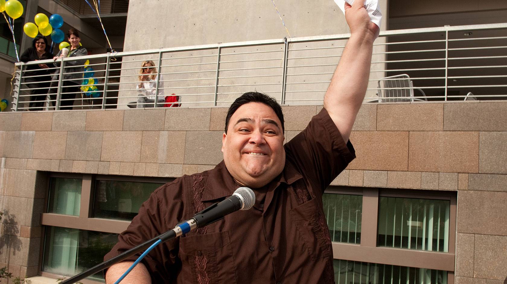 Marco Angulo raises his fist in the air triumphantly, clutching a piece of paper
