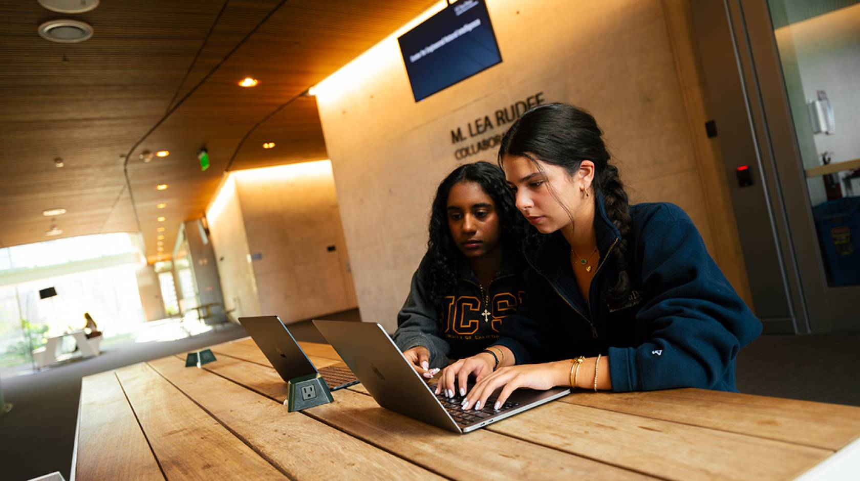 Two young women sit together looking at a computer