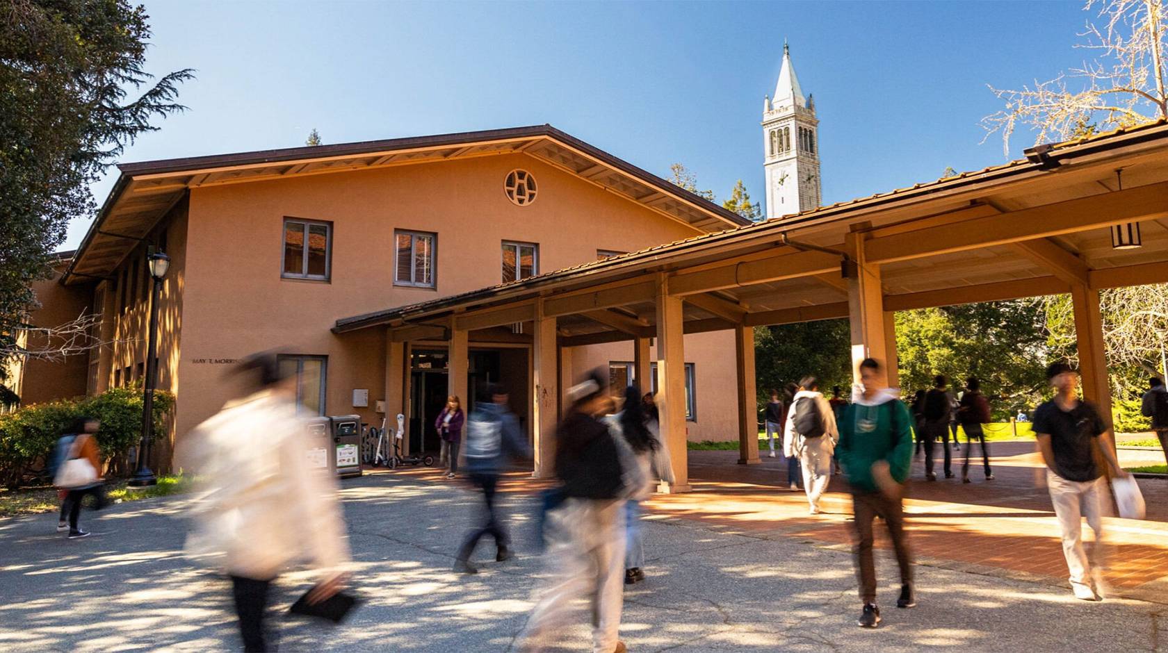 Students walk in front of the music building on Cal's campus, with the campanile in the background