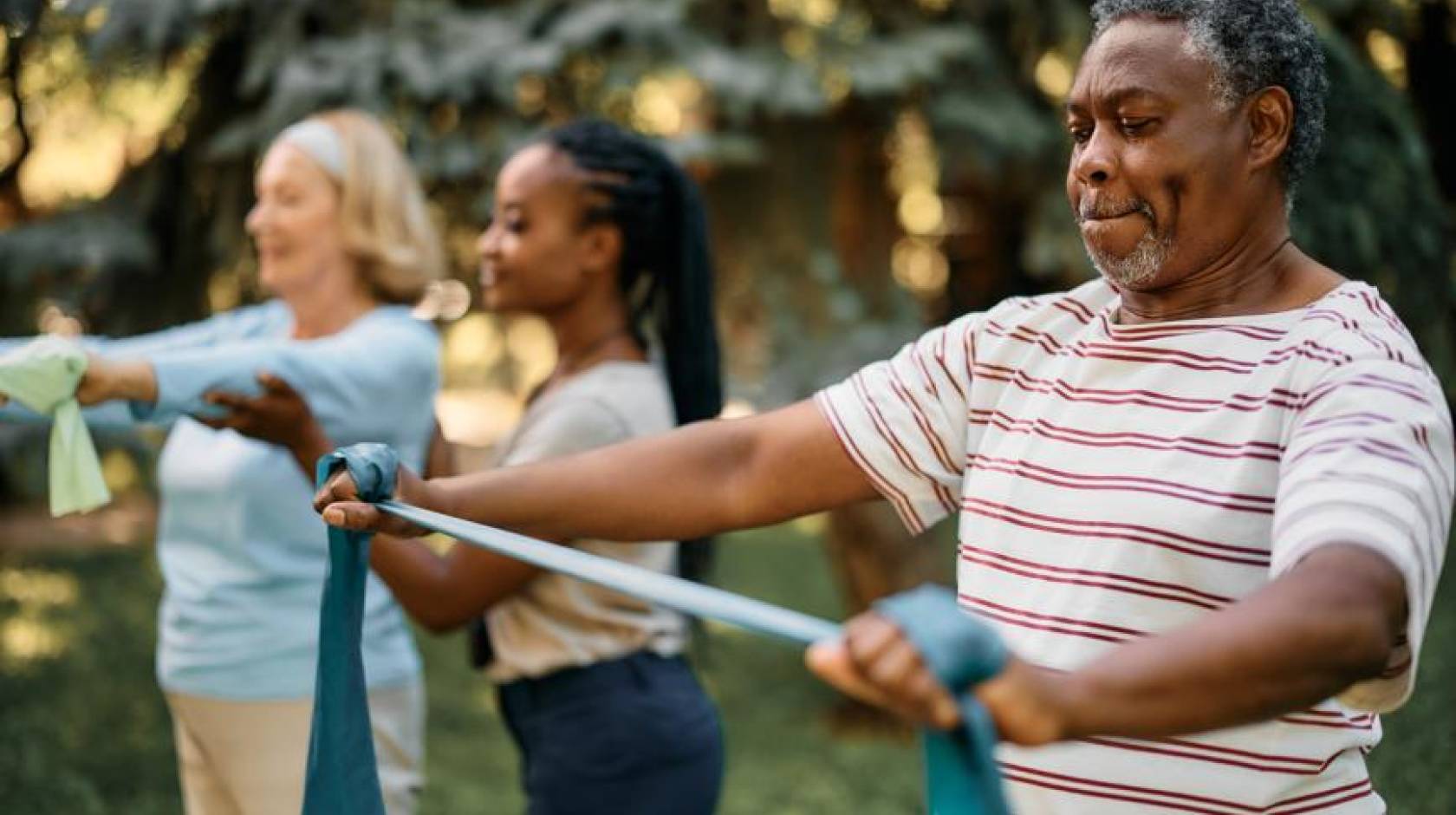 Three adults do exercises with stretchy bands