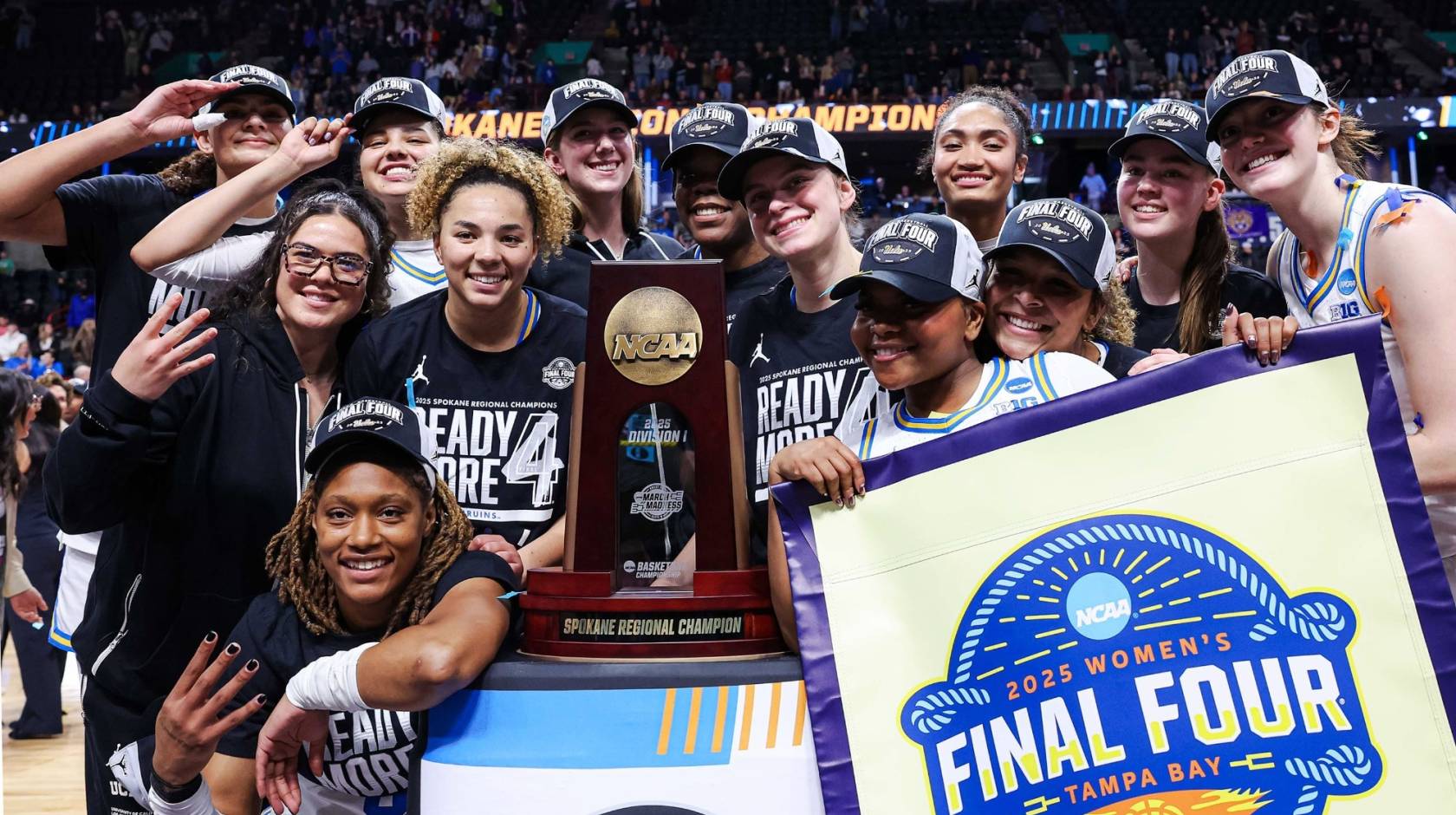 The UCLA women's basketball team in Final Four gear smiles for a group picture around the Spokane regional trophy