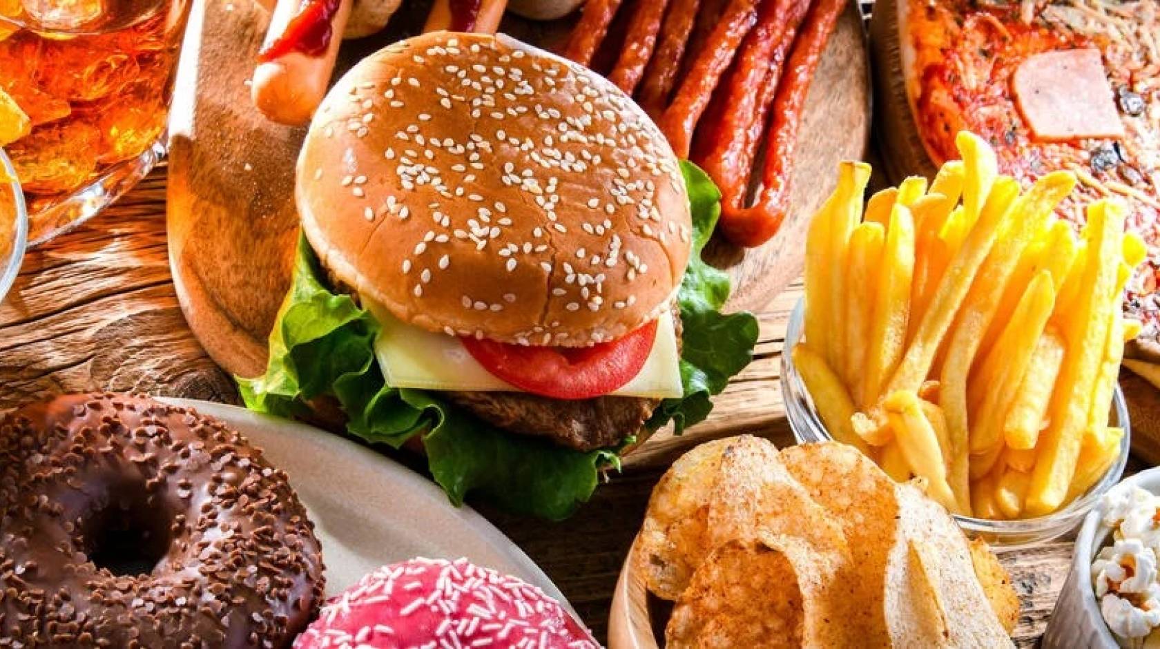A photo of a table with chips, beer, a burger, pizza, french fries, tacos and ribs