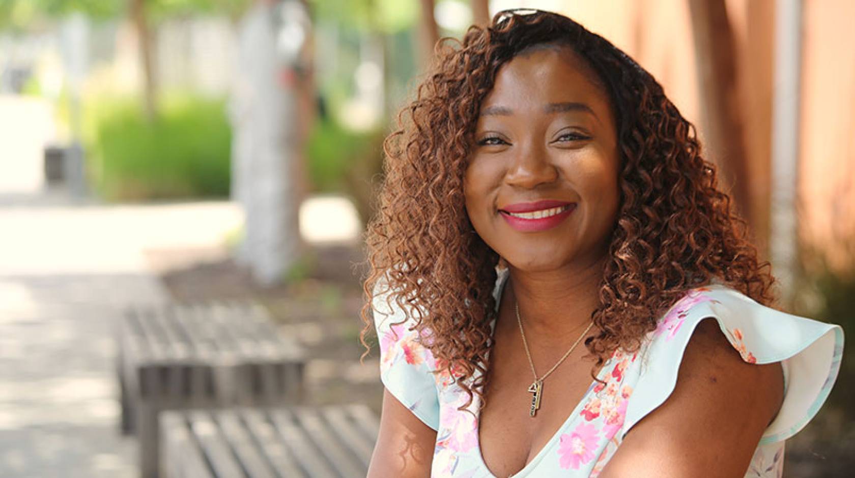 A woman smiles for a portrait, sitting on a bench