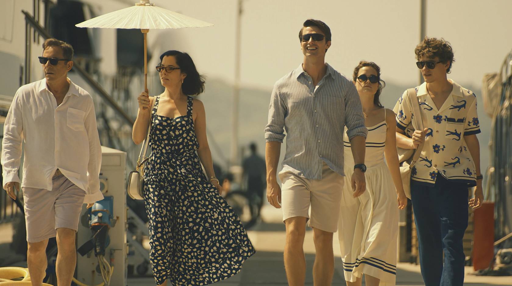 The five actors who play the Ratliff family walk down a gangplank on a pier together in a scene from The White Lotus