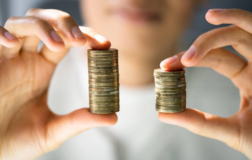 Close up of hands holding two stacks of coins, one larger than the otther
