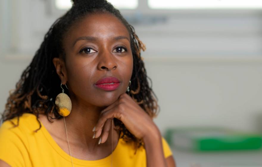 Sabrina Strings rests her chin on her hand and looks at the camera wearing a bold yellow shirt
