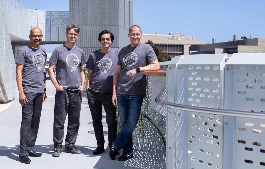 Four men in matching T-shirts standing outside