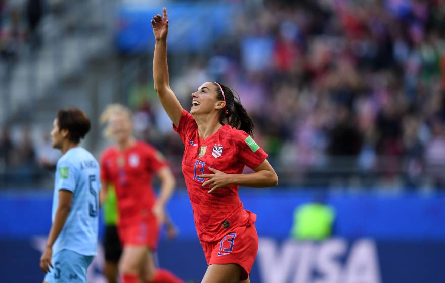 Alex Morgan pointing upward as she plays soccer for the US