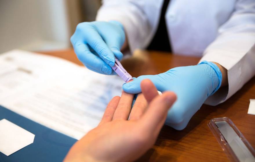Blood test on finger being administered
