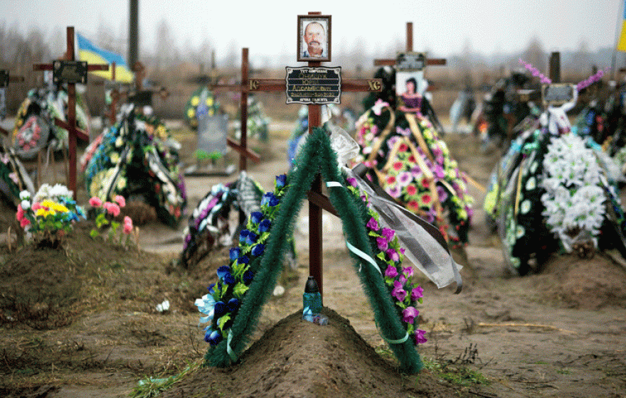 Photos on crosses covered in flowers mark graves in Bucha, Ukraine