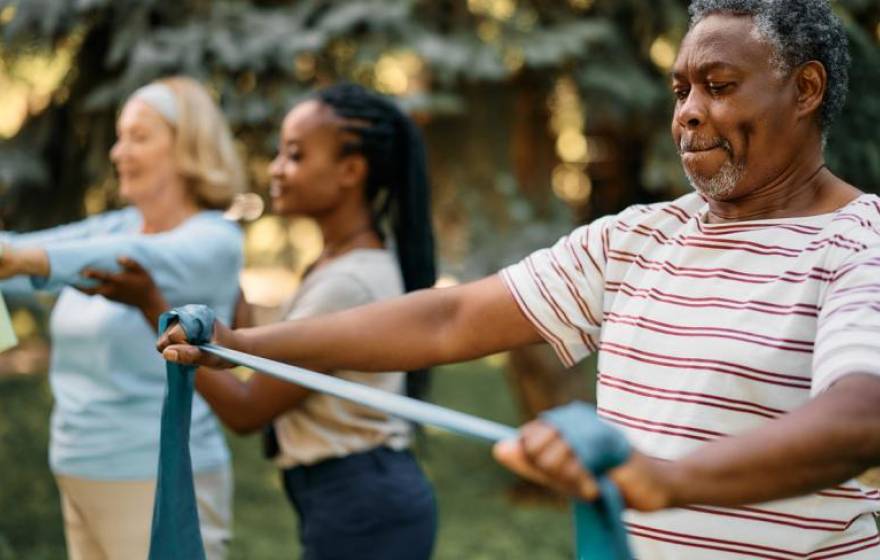 Three adults do exercises with stretchy bands
