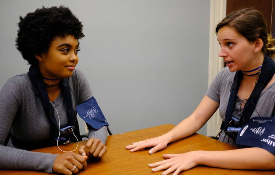 Two young people in blood pressure cuffs talking