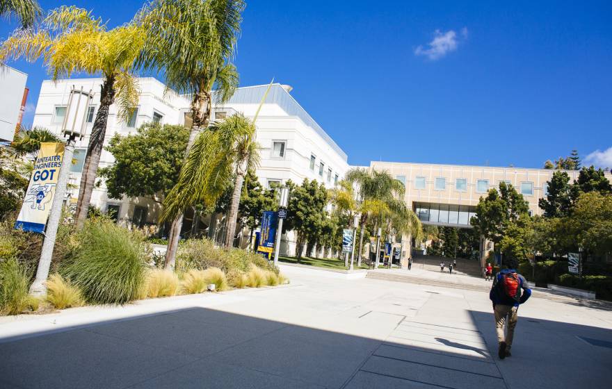 Student walks on wide pavement area of UC Irvine campus