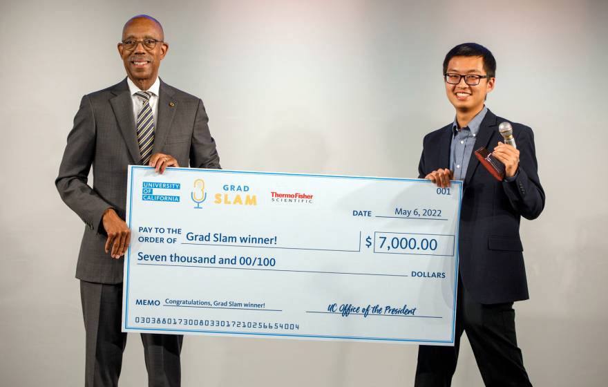 Justin Lee holds up his Grad Slam victory check with President Drake