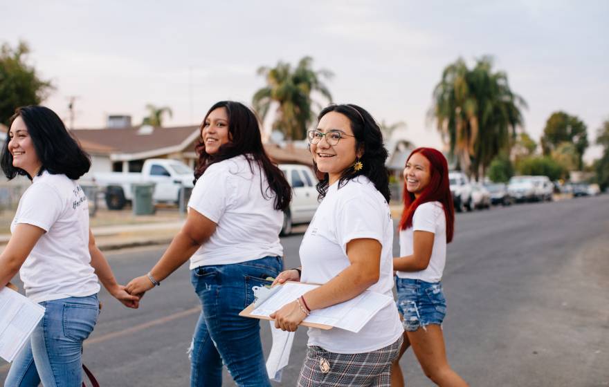 Four young women walking around a neighborhood in Delano doing voter registration
