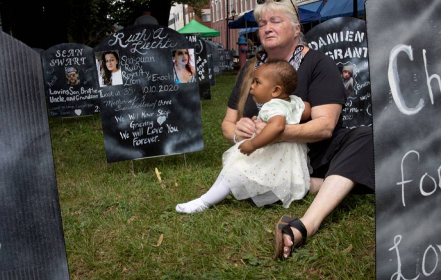 A woman holds a young child near an opiate memorial