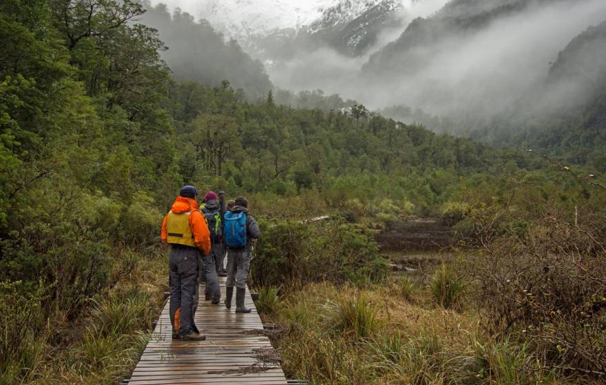 People on a boardwalk in Patagonia looking into foggy valley