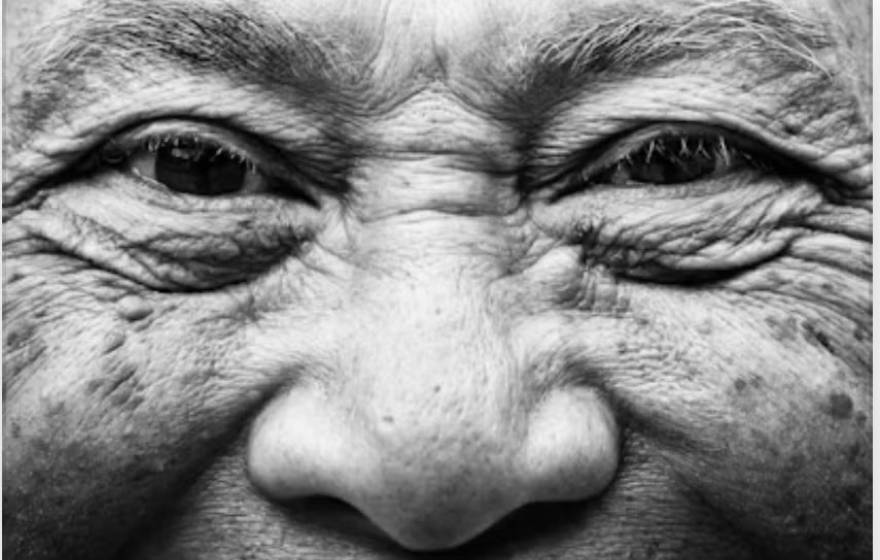 A close-up of an older person's smiling face and wrinkles