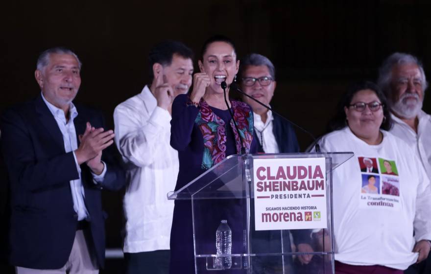 Claudia Sheinbaum pumps her first at a podium at a political rally