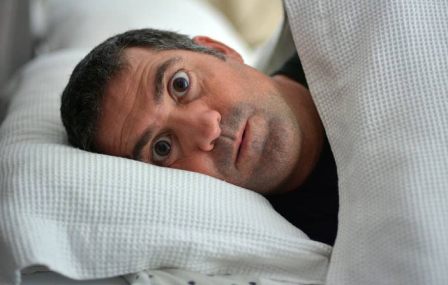 Man in bed looking surprised and scared