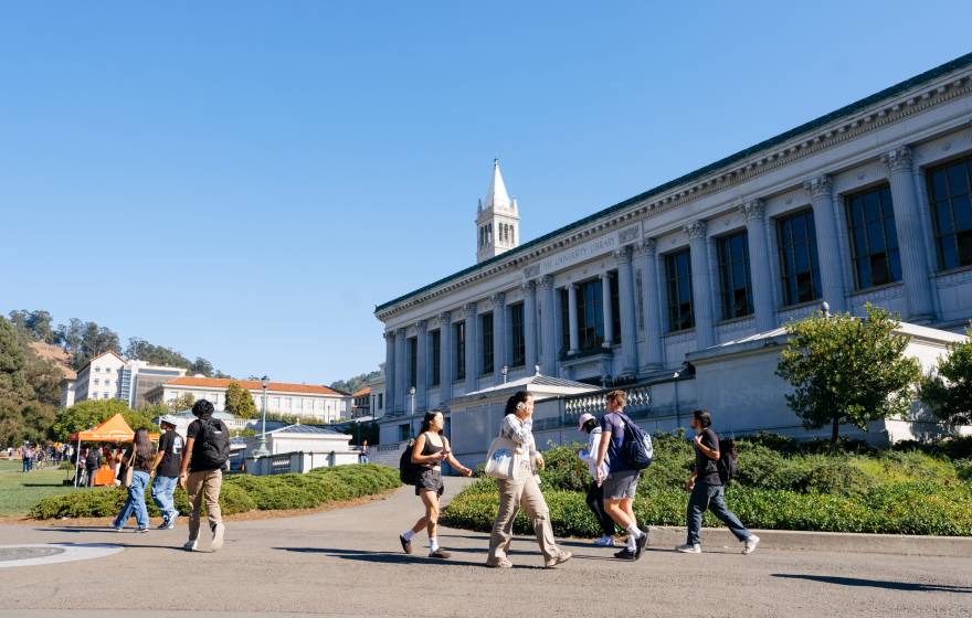 Students walk on the UC Berkeley campus, Campanile behind them