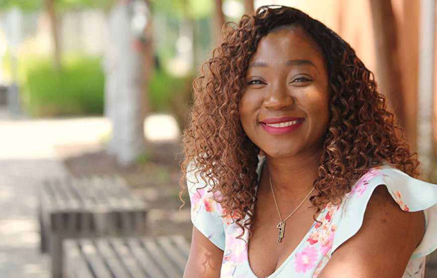 A woman smiles for a portrait, sitting on a bench