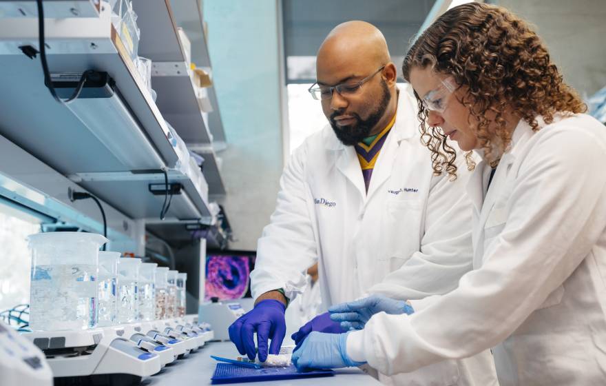 Two people in lab coats work in a lab together